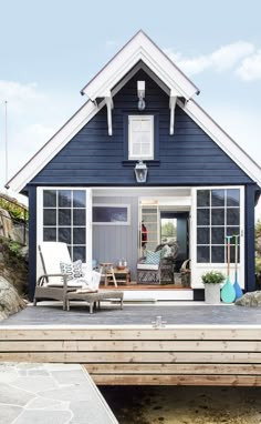 a blue house with white trim on the front door and windows, sitting next to a wooden deck