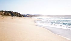 a person walking on the beach next to the ocean