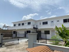 a white building with two balconies on the top floor and an iron fence around it