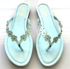 a pair of blue sandals with flowers and pearls on the toes, sitting on a white surface