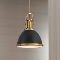 a black and gold pendant light hanging from a ceiling fixture in a room with white walls