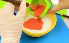 a person in white gloves is painting an orange and red substance on a yellow bowl