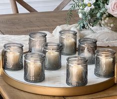 twelve glass candles on a tray with flowers in the background