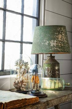 a lamp sitting on top of a wooden table next to a glass jar filled with sea shells