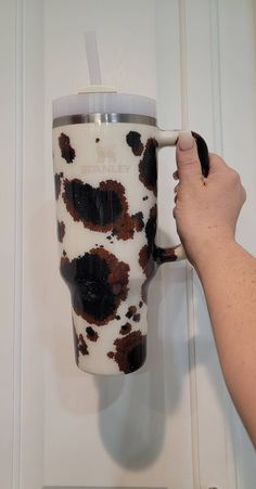 a person is holding a coffee cup in front of a white door with brown spots on it