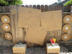 two cardboard boards with drawings on them next to some stools and a wooden fence