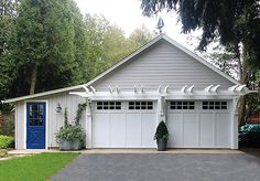 a white garage with blue doors and two planters on the side of the garage