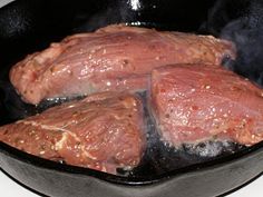 steaks cooking in a skillet on the stove