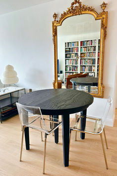 a dining table with chairs around it in front of a bookshelf full of books