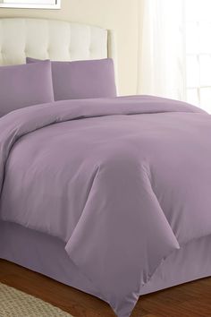 a bed with purple sheets and pillows in a room