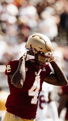 a football player is holding his head in one hand and wearing a helmet on the other