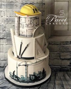 a three tiered cake with construction drawings on it's sides and a yellow hard hat on top