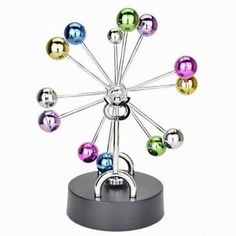 a multicolored metal ferris wheel sculpture on a black stand with silver rings around it