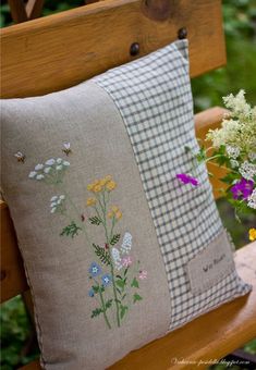 a wooden bench with a pillow and flowers on it