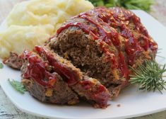 meatloaf with sauce and mashed potatoes on a white plate, ready to be eaten