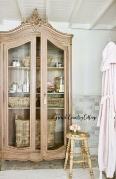 an old china cabinet with wicker baskets on top and the words french country cottage above it