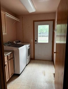 an empty kitchen with a washer and dryer next to the door that is open