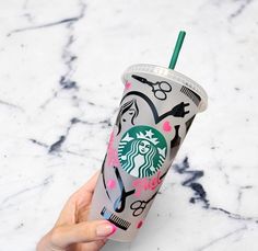 a hand holding a starbucks cup with scissors and hairbrushes on the side,