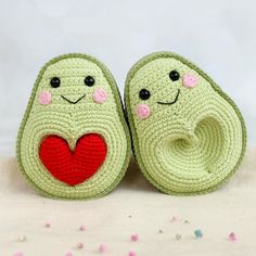 two crocheted slippers with faces and hearts on them sitting on a white surface