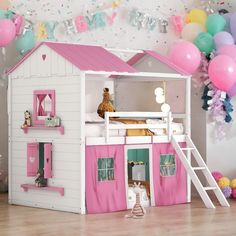 a pink and white doll house with balloons in the background