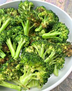 a white bowl filled with broccoli on top of a wooden table