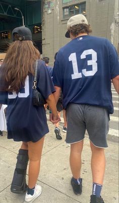 two people walking down the street in shorts and t - shirts with numbers on them