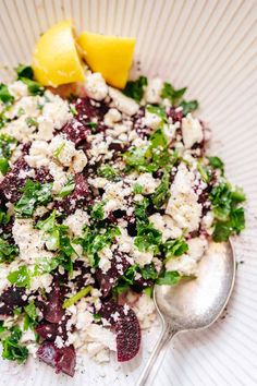 a salad with feta cheese and lemon wedges