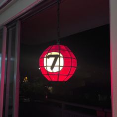 a red and white light hanging from the side of a window in front of a building