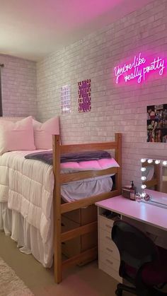 a bedroom with a bed, desk and mirror on the wall next to a white brick wall