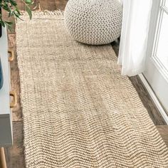 a rug on the floor in front of a window with a potted plant next to it