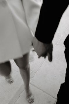 two people holding hands while walking down the street