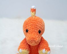 an orange crocheted elephant sitting on top of a white blanket