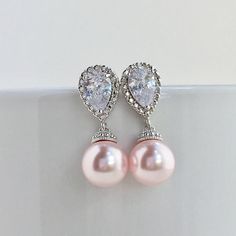 Classic cubic zirconia and pearl bridal earrings in rhodium plated brass setting. Earrings feature teardrop clear cubic zirconia ear post and 10mm Swarovski rosaline pink pearl dangle drop. Total length of the earrings is 2.7 cms. For match necklace click: https://www.etsy.com/listing/514758984/pink-pearl-necklace-blush-pink-bridal?ref=listing-shop-header-3 For complete set click: https://www.etsy.com/listing/528565041/rose-bridal-pearl-set-blush-pink-crystal?ref=listing-shop-header-2 To browse Rose Pink Wedding, Match Necklace, Bridal Pearl Earrings, Blush Pink Bridesmaids, Pink Pearl Earrings, Pink Pearl Necklace, Gold Bridal Earrings, Pink Swarovski, Rose Blush