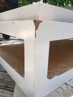 an unfinished piece of white wood sitting on top of a wooden floor next to a tree