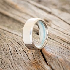 a wedding ring sitting on top of a piece of wood with blue and white stripes