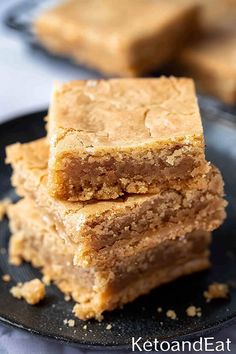 three pieces of peanut butter bars stacked on top of each other in a black plate