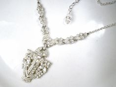 "Offering a gorgeous antique 1920's - 1930's era Art Deco French paste pave rhinestone Flapper pendant lavaliere necklace perfect for the Bride! I absolutely adore this necklace! The SO Art Deco ornate geometric shaped shiny silver pot metal pendant is lavishly encrusted with marquise and baguette cut as well as small round cut closely pave set brilliantly clear sparkly crystal rhinestones. The pendant hangs from ornate links that compliment the pendant so well and are adorned with more clear sp Art Deco Rhinestone Jewelry For Wedding, Art Deco Crystal Necklace For Wedding, Art Deco Wedding Jewelry With Rhinestones, Antique Bridal Necklace With 17 Jewels For Wedding, Antique Crystal Wedding Necklaces, Antique Crystal Necklaces For Wedding, Flapper 1920s, 20s Wedding, 1930s Wedding