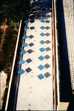 an aerial view of blue chairs and tables on the ground in front of a building