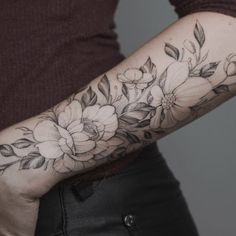 a woman's arm with flowers and leaves tattooed on the left side of her arm