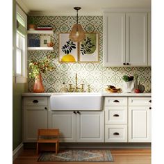 a kitchen with white cabinets and green wallpaper