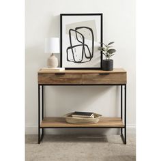 a wooden table with two drawers and a black frame on the wall next to it