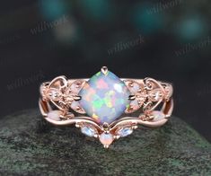 a ring with an opal stone in the center on top of a green rock