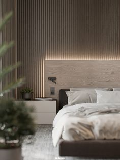 a bed with white sheets and pillows in a bedroom next to a potted plant