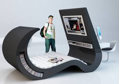 an unusual bed that looks like a computer monitor and dvd player is in the shape of a crescent