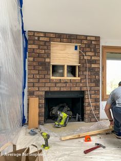 a man working on a brick fireplace in a room under construction with wood framing around it