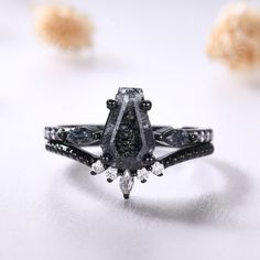 a black diamond ring sitting on top of a white table next to other diamonds and stones