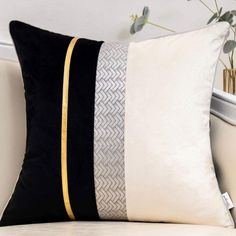 two black and white pillows sitting on top of a bed next to a vase with flowers