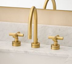 two gold faucets on a marble counter top