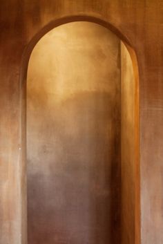 an arched doorway leading to another room with a bench in the corner and light shining on the wall