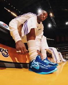 the basketball player is tying his shoes before going to the court for a game against the lakers